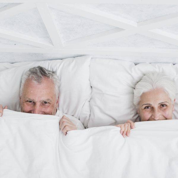 couple de seniors souriants dans un lit