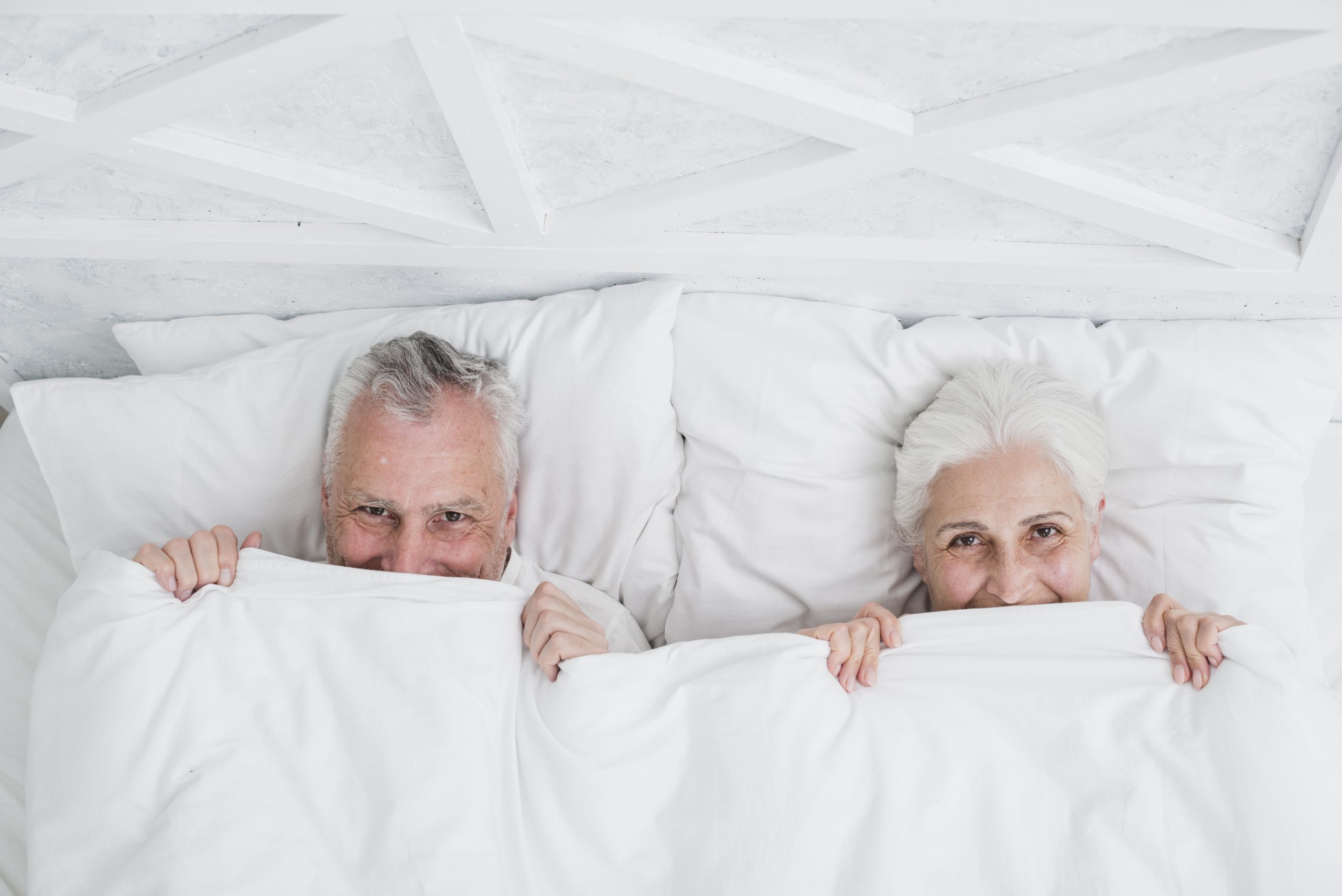 couple de seniors souriants dans un lit