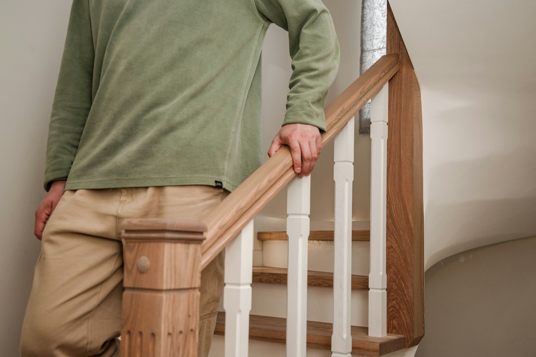 Une personne s'accroche à la main courante d'un escalier — risque de chute à domicile