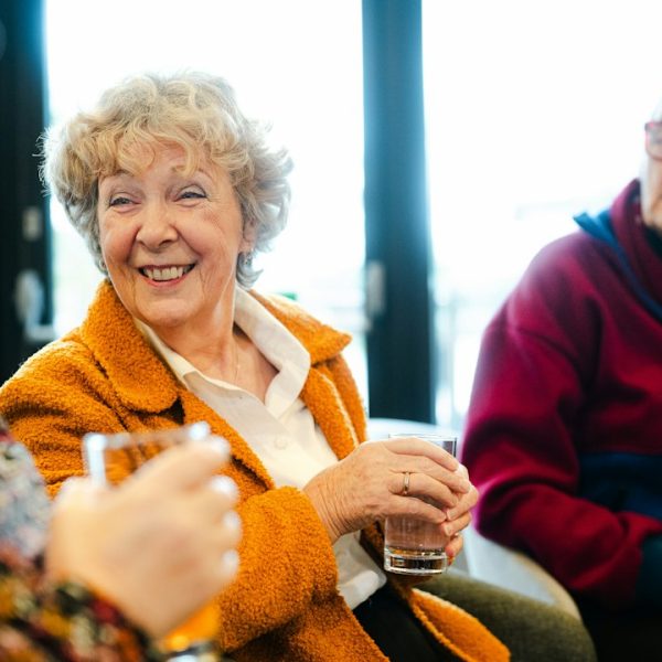 Trois seniors qui discutent et sourient ensemble dans un espace commun de résidence services