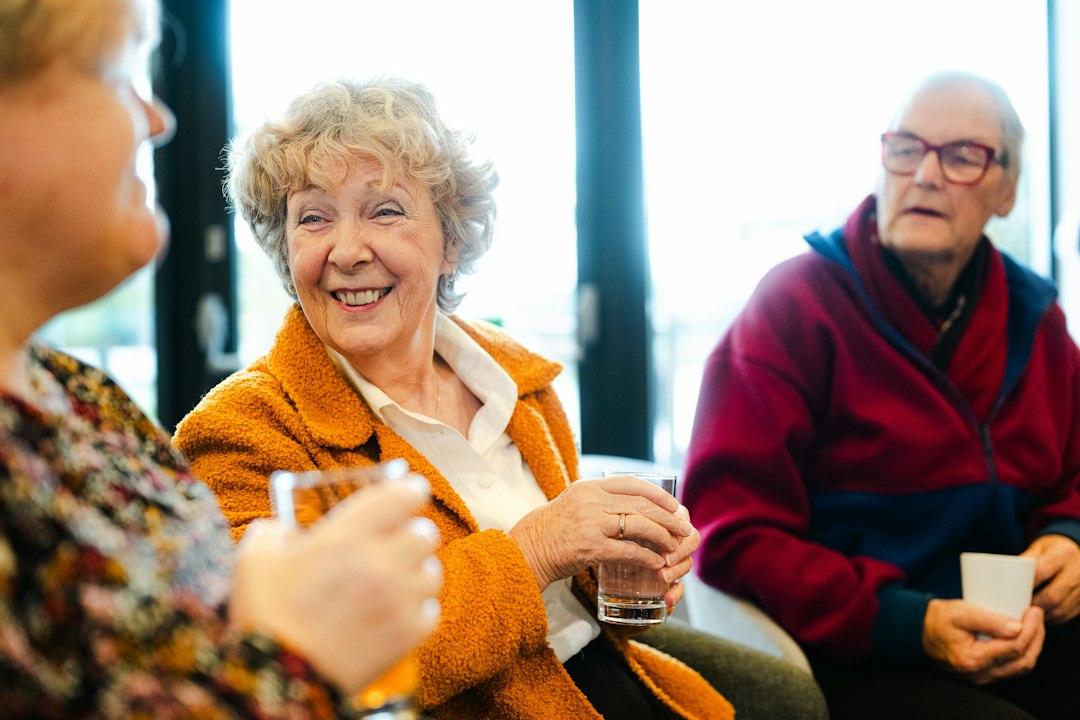 Trois seniors qui discutent et sourient ensemble dans un espace commun de résidence services